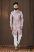 A toddler wearing a pink woven jacquard kurta with white pyjamas for a festive occasion