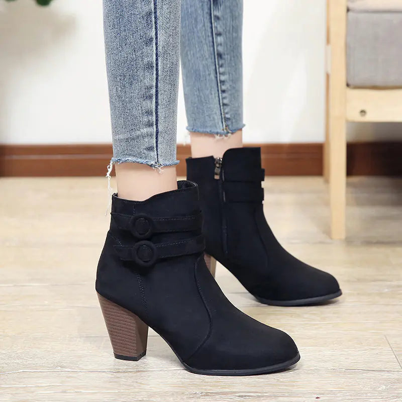Side view of women's black suede ankle boots with chunky heels and decorative side buckles