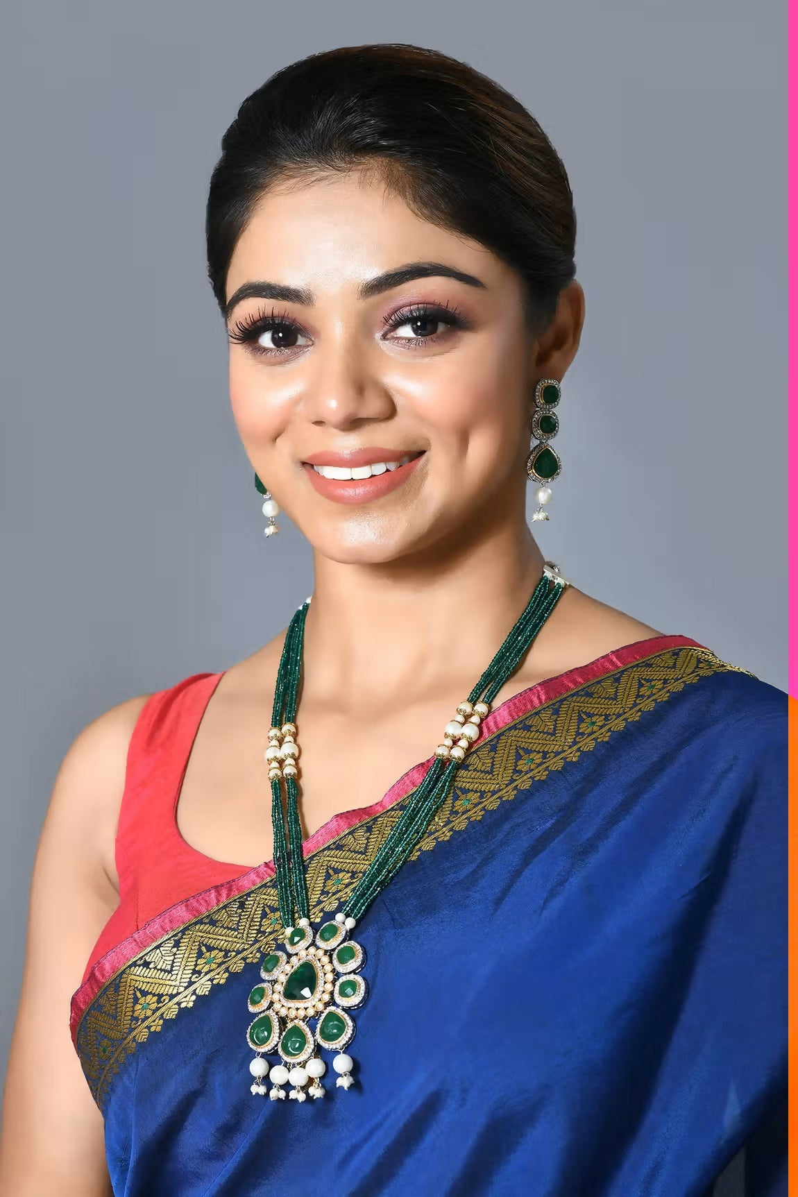 Golden, white, and green Jadau Kundan pendant set with matching earrings on a neutral background.