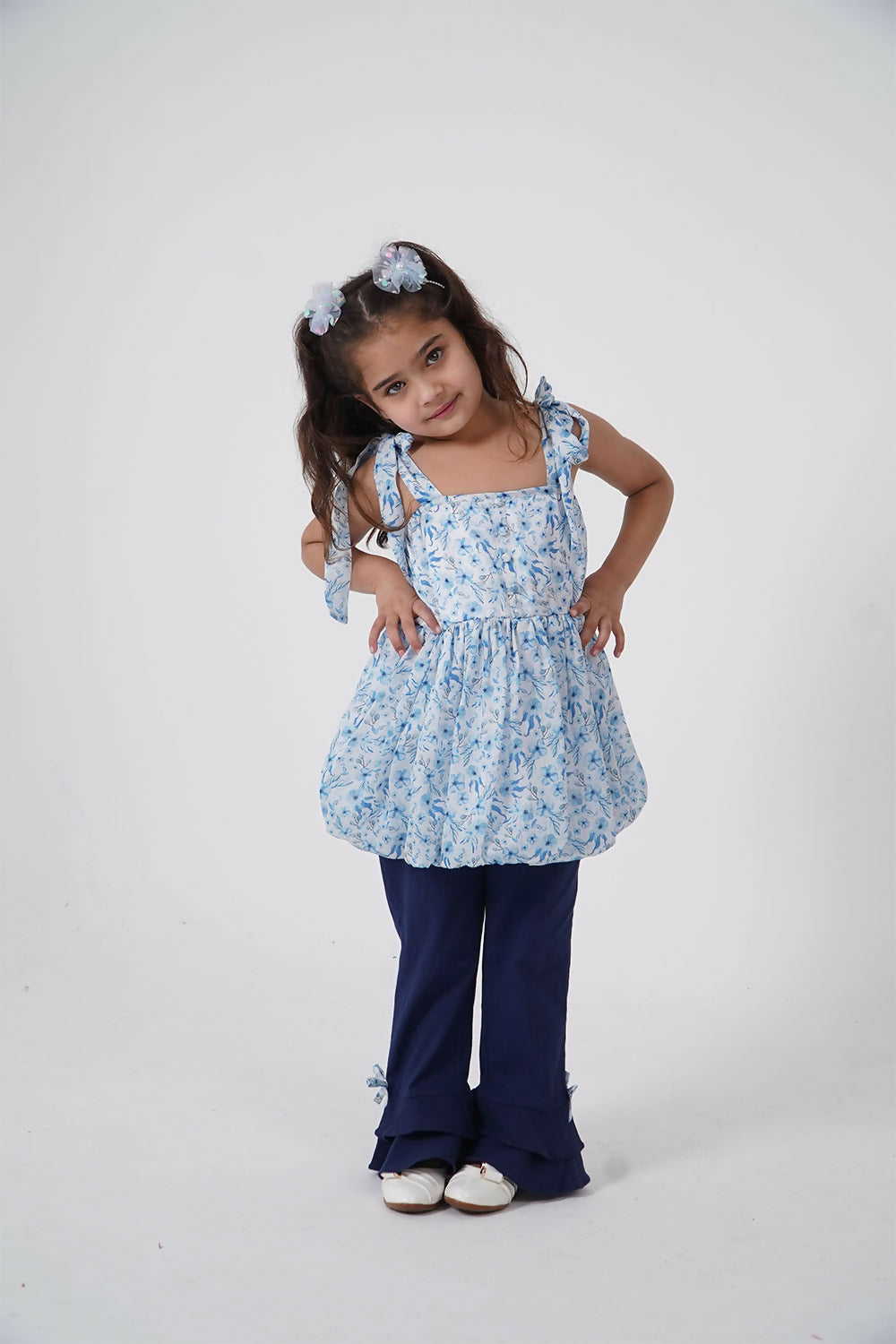 A two-piece set for girls featuring a blue floral chiffon balloon top with shoulder ties and matching flared trousers.