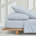 Australian cotton sateen sheet set on a wooden platform bed showing solid and striped color options.