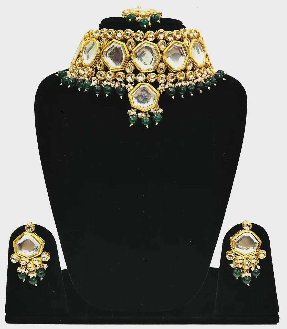 A luxurious green Kundan stone studded jewellery set with gold-plated alloy finish on a neutral background.