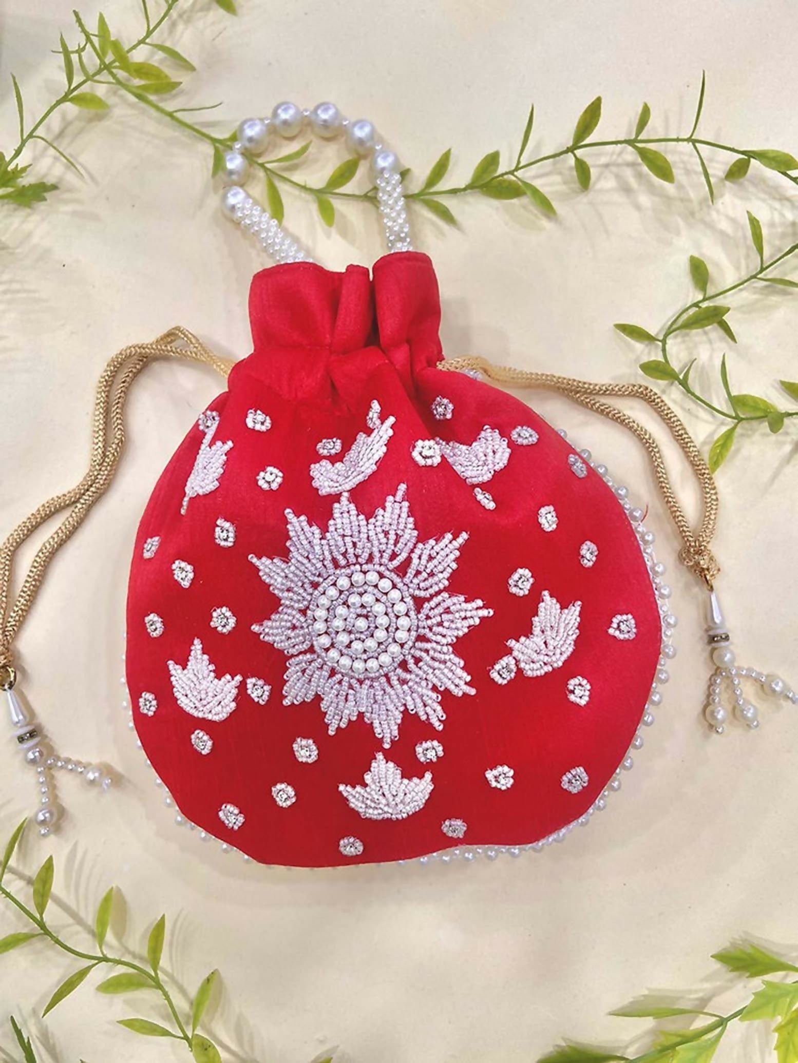 A vibrant red synthetic potli bag featuring elegant pearl hand-work detailing, isolated for ethnic styling.