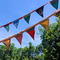 Vibrant, multi-colored sari flag wall art in shades of burnt orange, blue, mustard, and magenta, styled in a bohemian home.