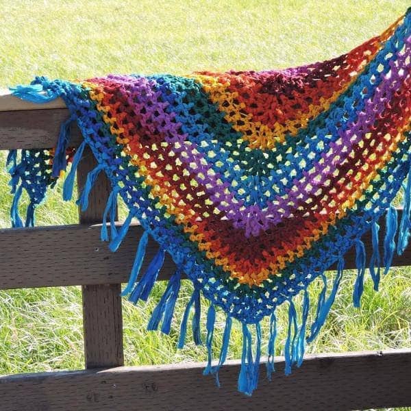 Colorful rainbow geometric crochet shawl draped on a model in a bohemian style