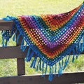 Colorful rainbow geometric crochet shawl draped on a model in a bohemian style