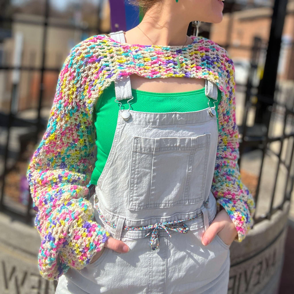 Close-up of Rainbowlero crochet sleeves featuring multicolor flecks on a cream knit fabric.
