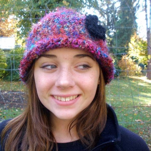Vibrant multi-colored crochet cloche hat with black accents in a bohemian style