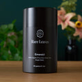 Emerald branded canister of organic Pi Lo Chun single estate green tea on a wooden surface.