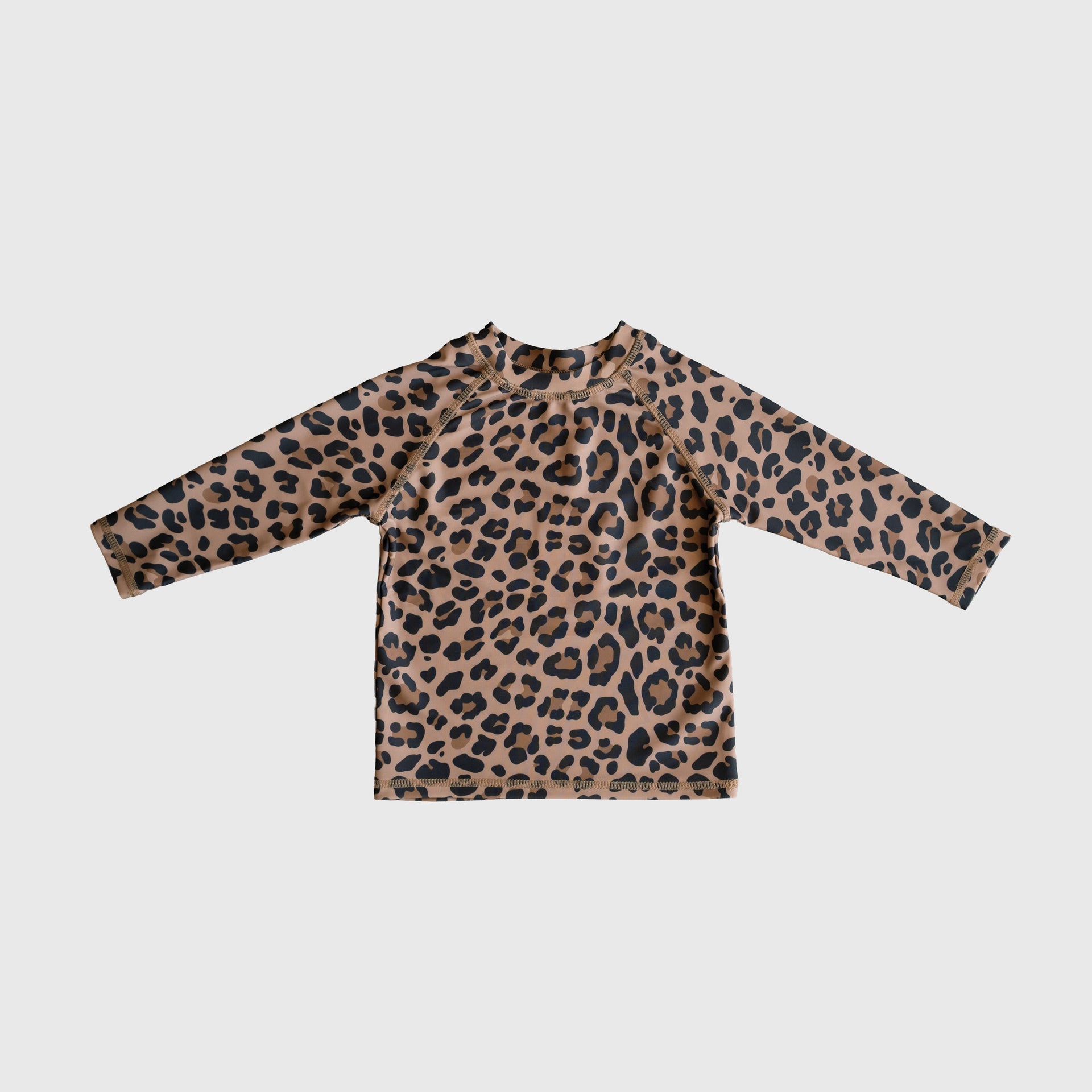 Child wearing a long-sleeve leopard print rash guard with a crew neckline at the beach