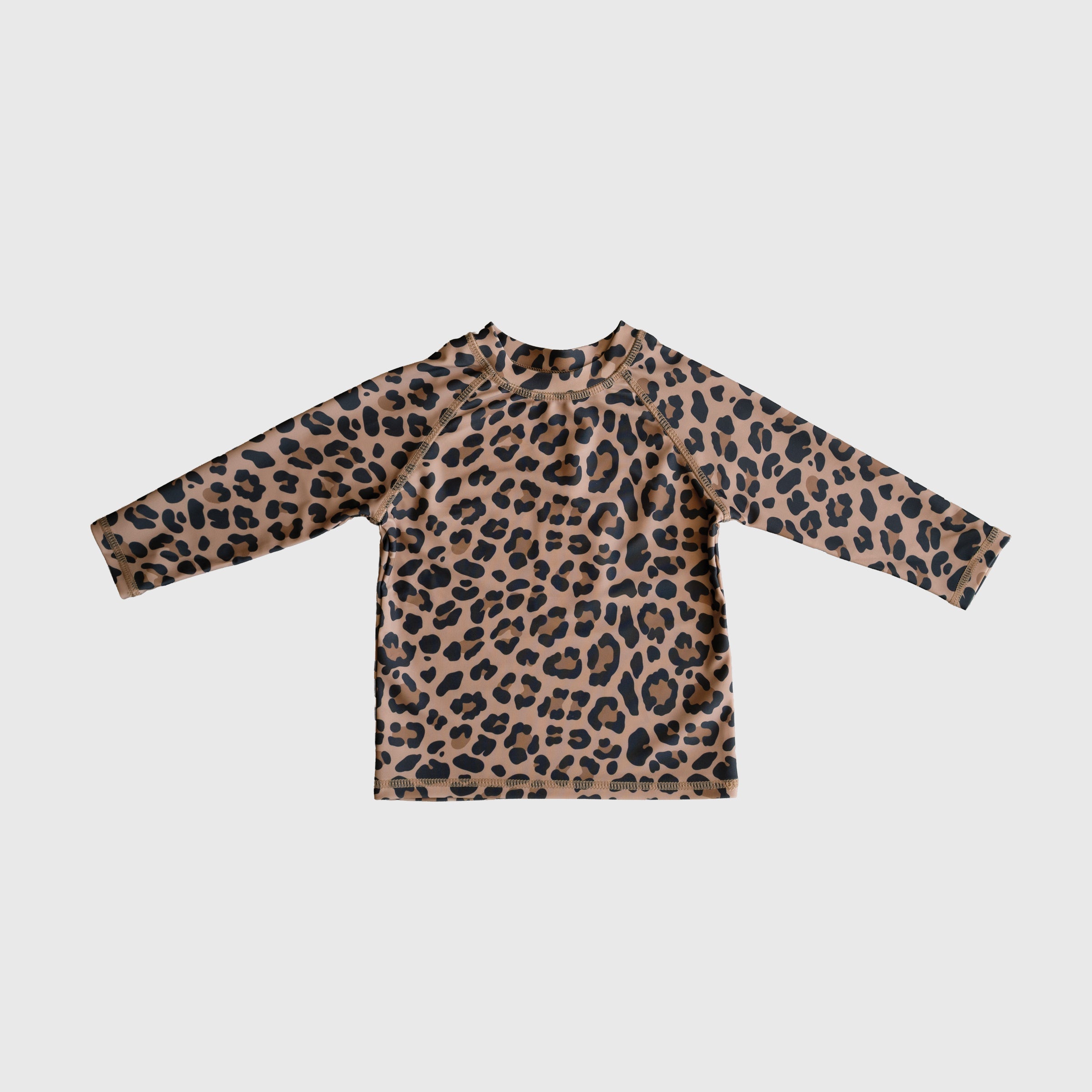 Child wearing a long-sleeve leopard print rash guard with a crew neckline at the beach