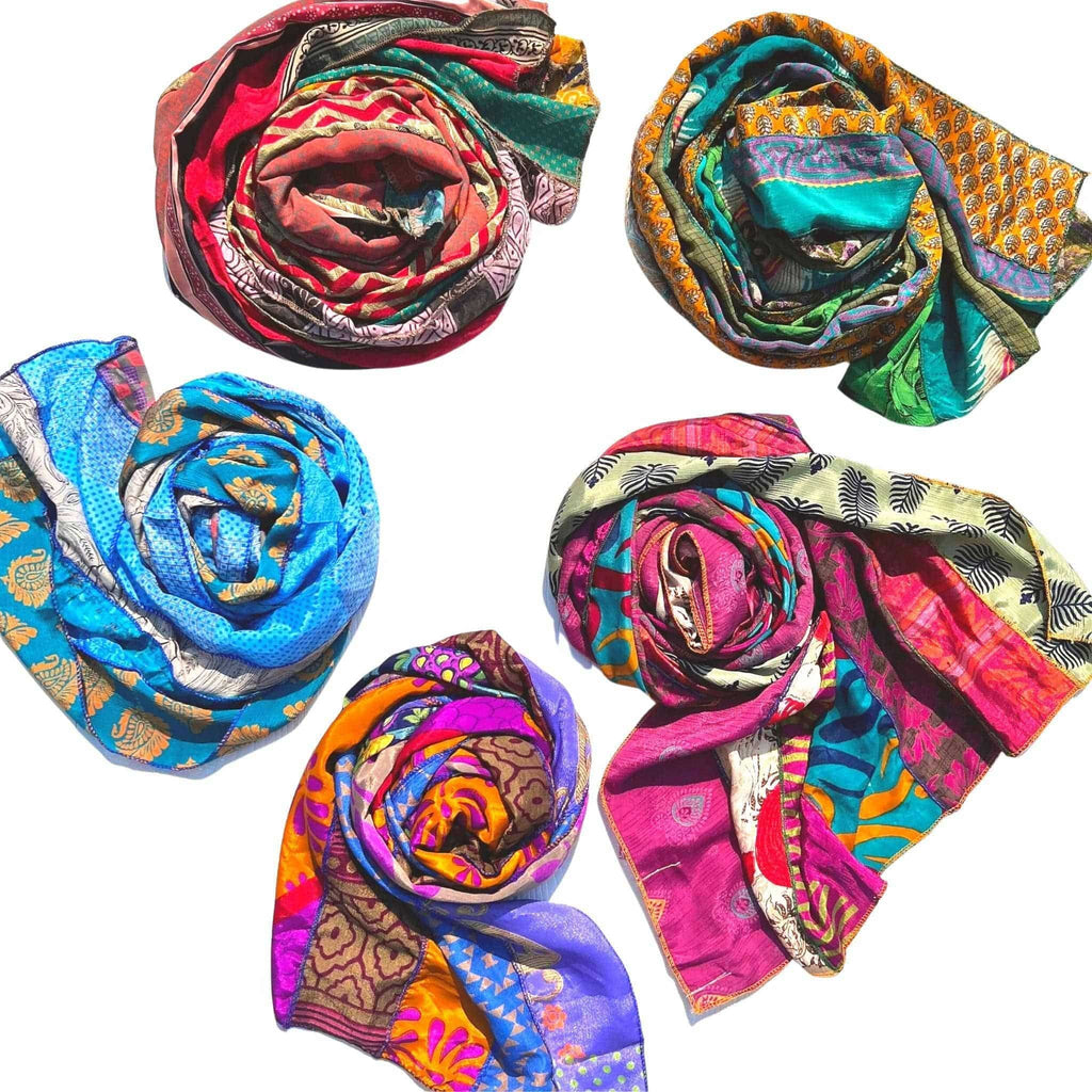 A long, vibrant bohemian silk scarf featuring abstract patterns in teal, magenta, marigold, and orange draped over a person.