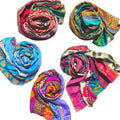 A long, vibrant bohemian silk scarf featuring abstract patterns in teal, magenta, marigold, and orange draped over a person.