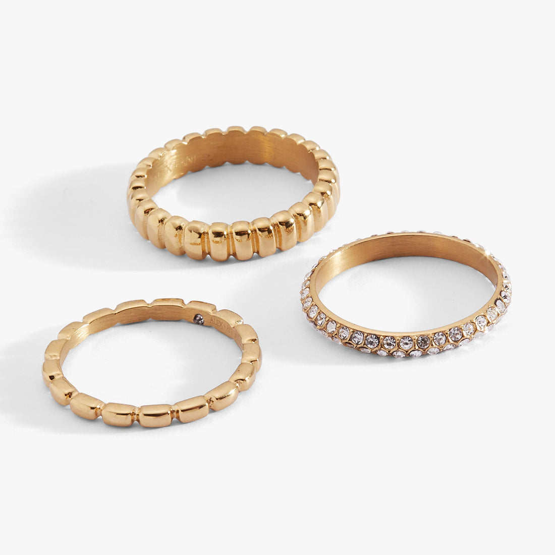 Set of three ribbed stacking rings in mixed gold and silver tones with clear crystal pave accents.