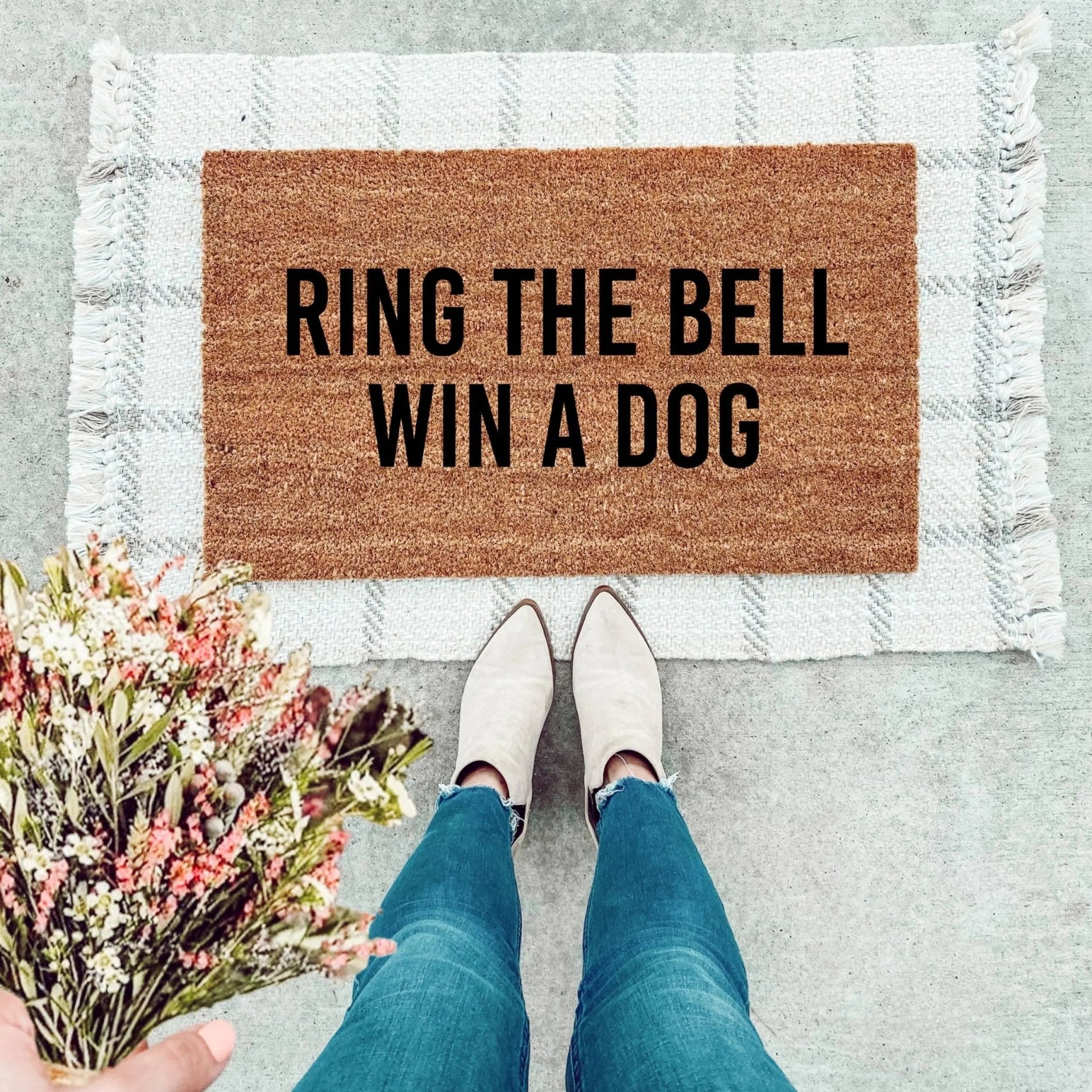 Farmhouse style natural coir doormat with 'Ring The Bell, Win A Dog' black typography at a front entryway.