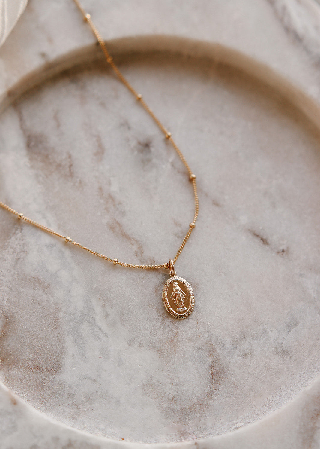 Gold necklace with a pendant on a marble surface