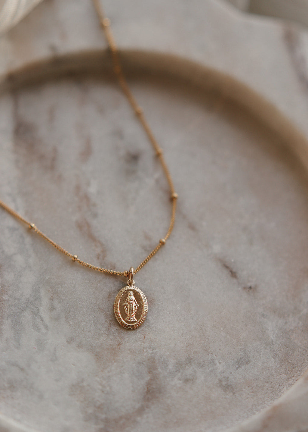 Gold necklace with a pendant on a marble surface