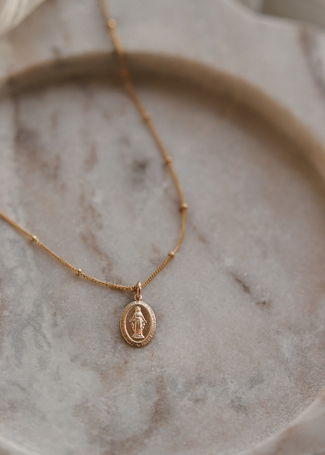 Gold necklace with a pendant on a marble surface
