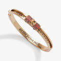 Shiny gold bangle bracelet with a gliding car charm, dotted road detail, and red and maroon stone accents.