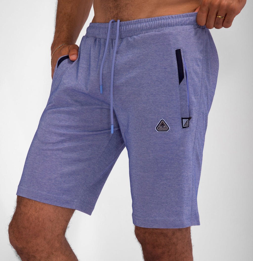 Man wearing blue, tall-fit athletic shorts with drawstring waist and pockets