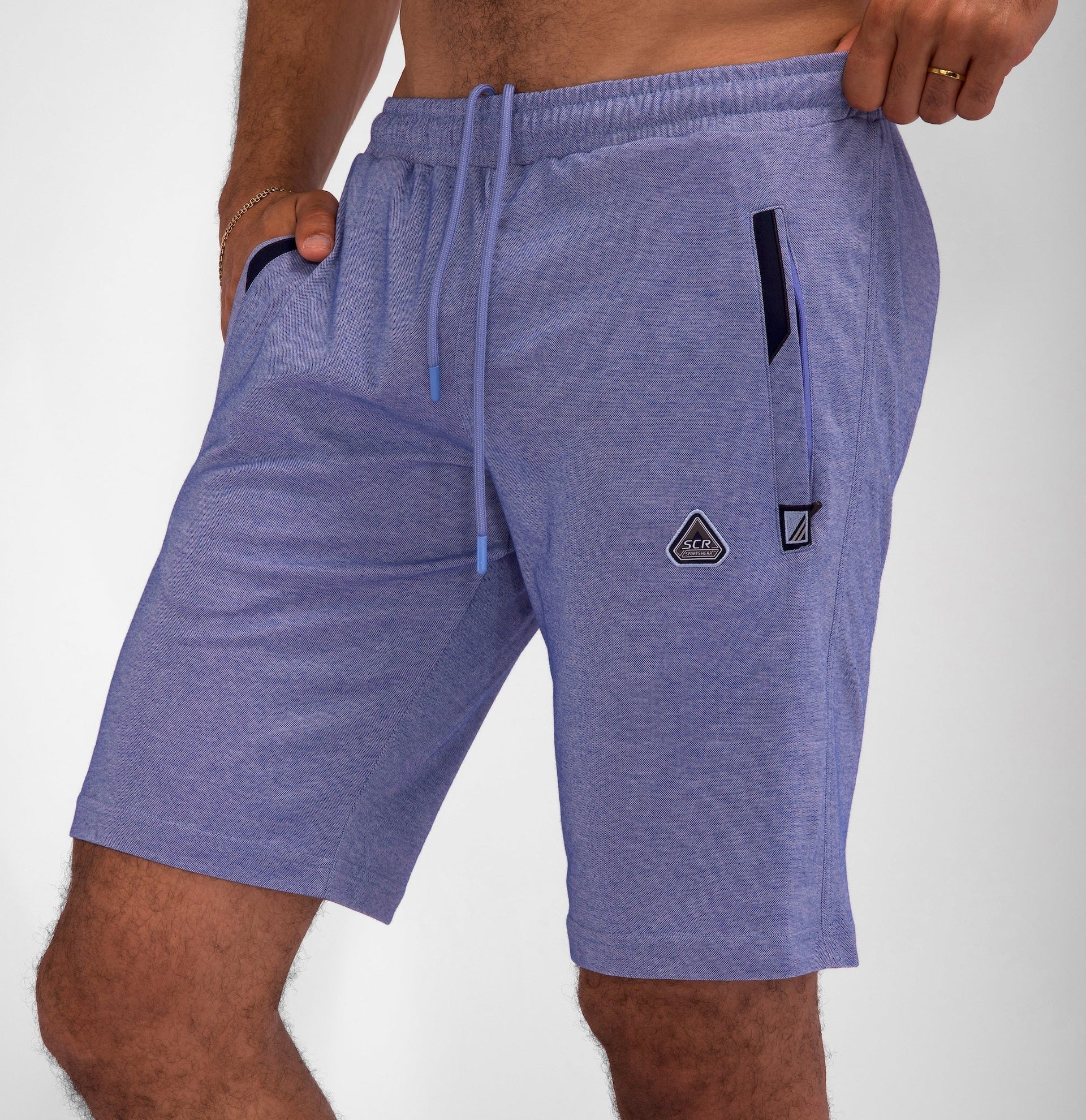 Man wearing blue, tall-fit athletic shorts with drawstring waist and pockets