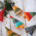 A set of handmade colorful cotton rustic Christmas trees arranged on a wooden table.
