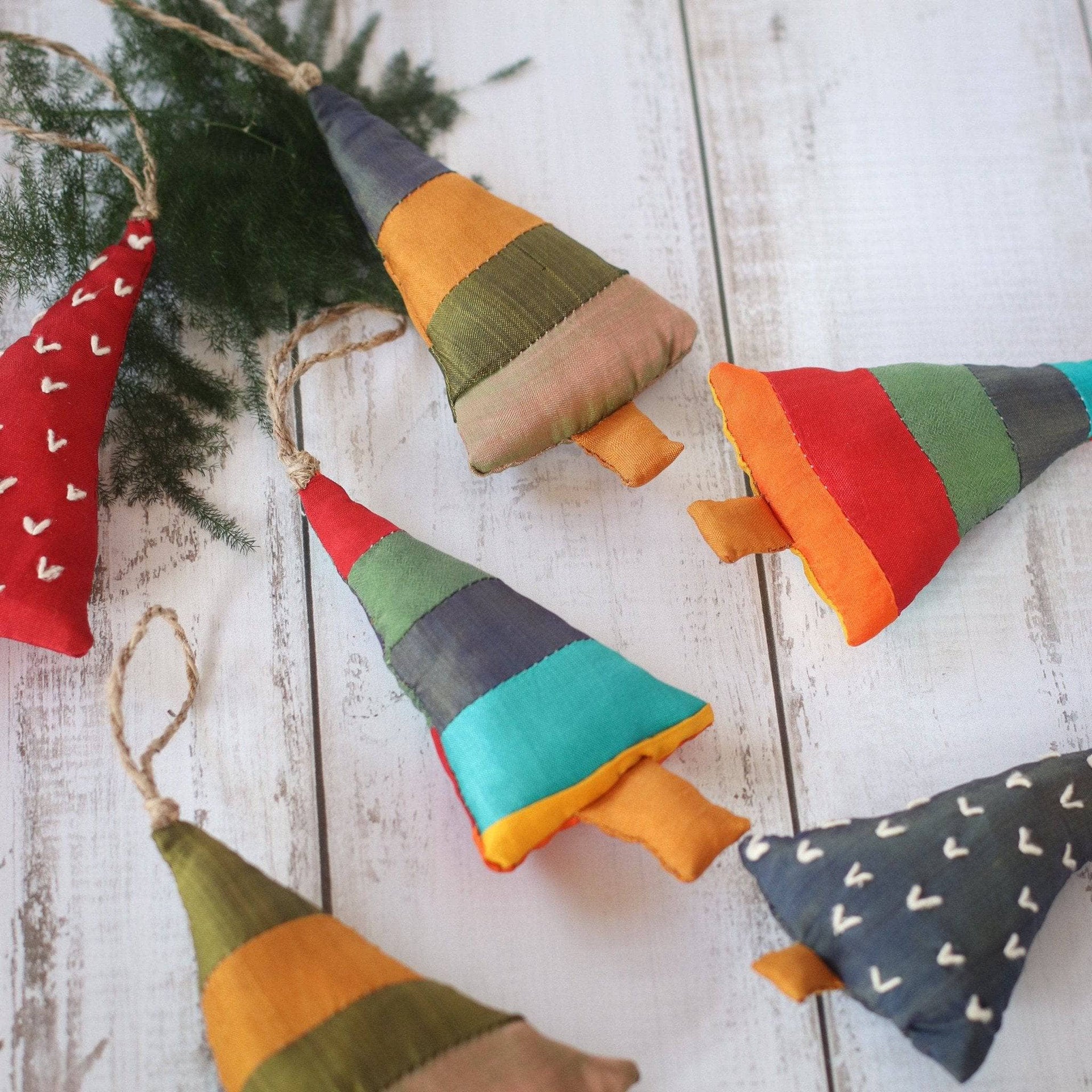 A set of handmade colorful cotton rustic Christmas trees arranged on a wooden table.