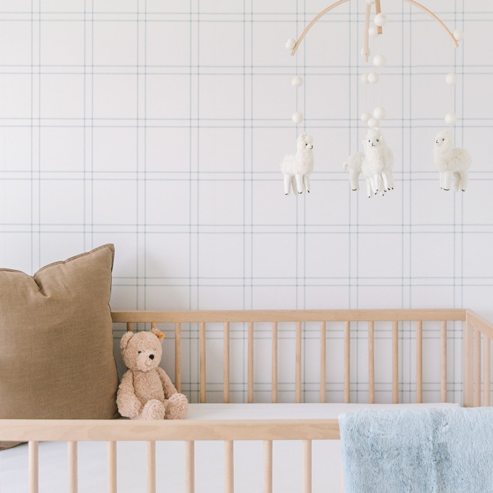 Lyle plaid wallpaper in blue and white in a minimalist nursery setting.