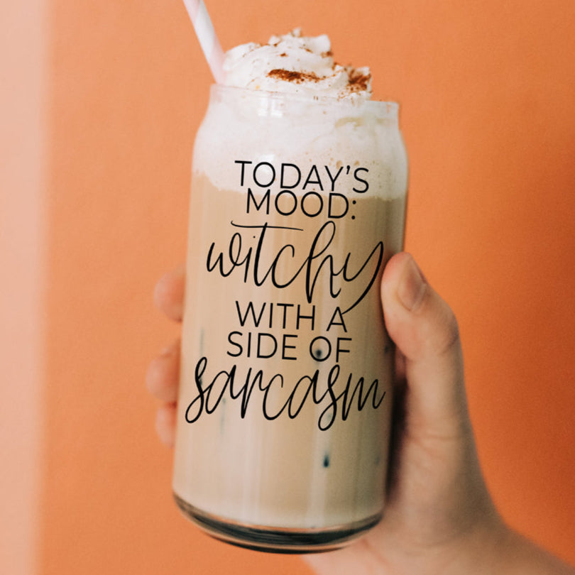A 20oz clear glass tumbler featuring the text 'Today's Mood: Witchy With a Side of Sarcasm' held in a hand.