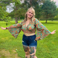 Model wearing a unique, vibrant recycled sari wrap top with dramatic bell sleeves.