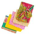 Vibrant sari silk Furoshiki wrap in pink, yellow, green, and orange used as gift wrapping and a head scarf.