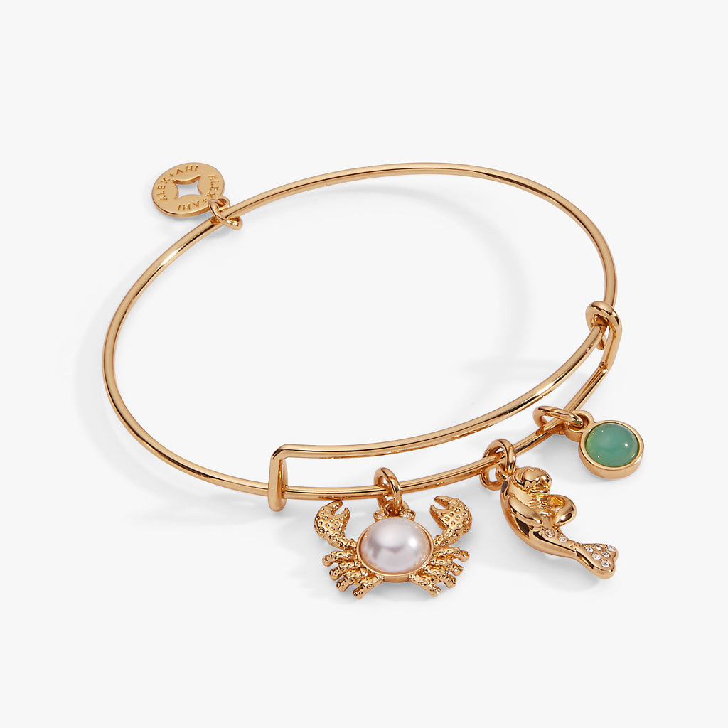 Gold-tone charm bangle featuring a pearl crab, crystal manatee, and aquamarine stone.