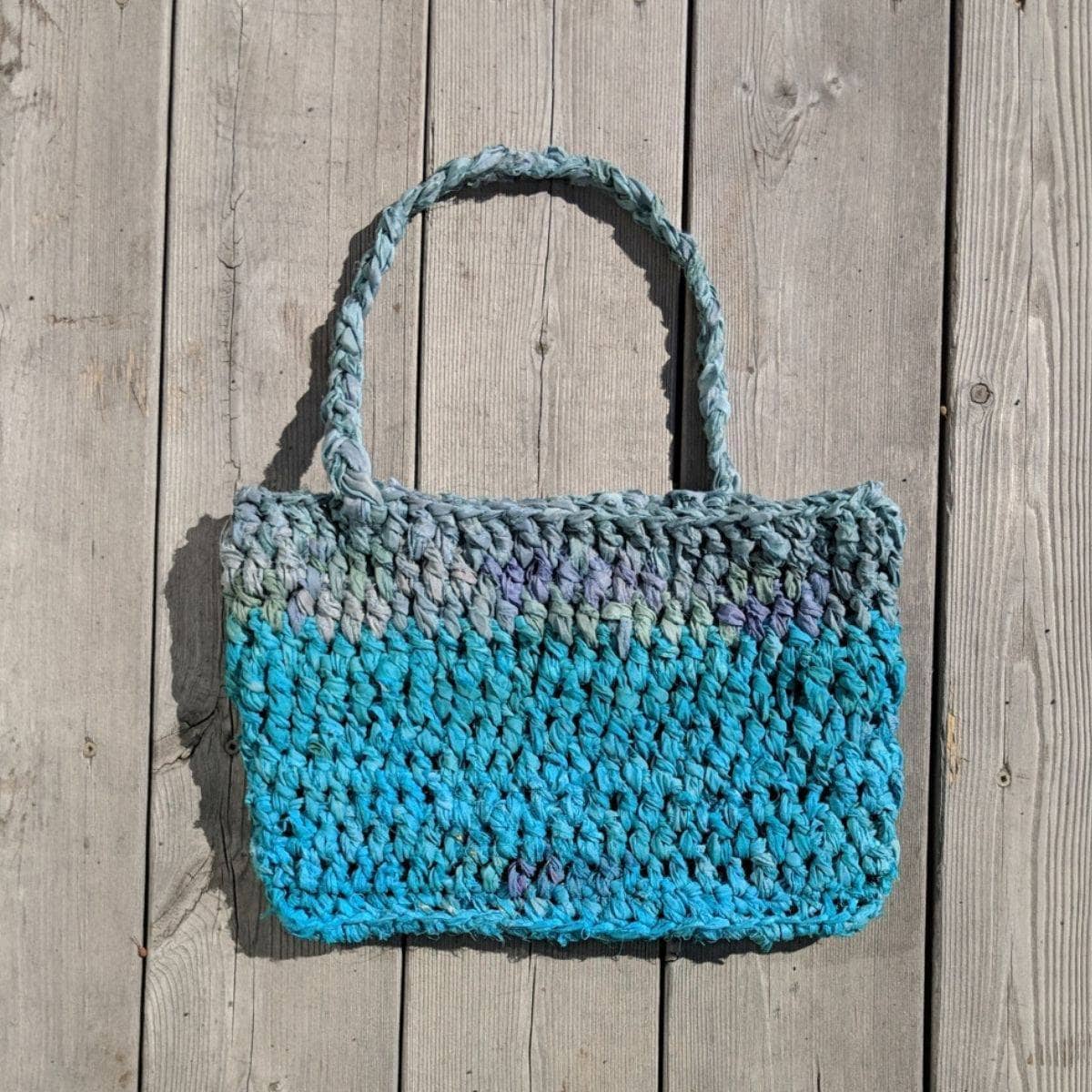 Sea Waves Beach Bag crochet pattern featuring teal, blue, and grey textured silk yarn.