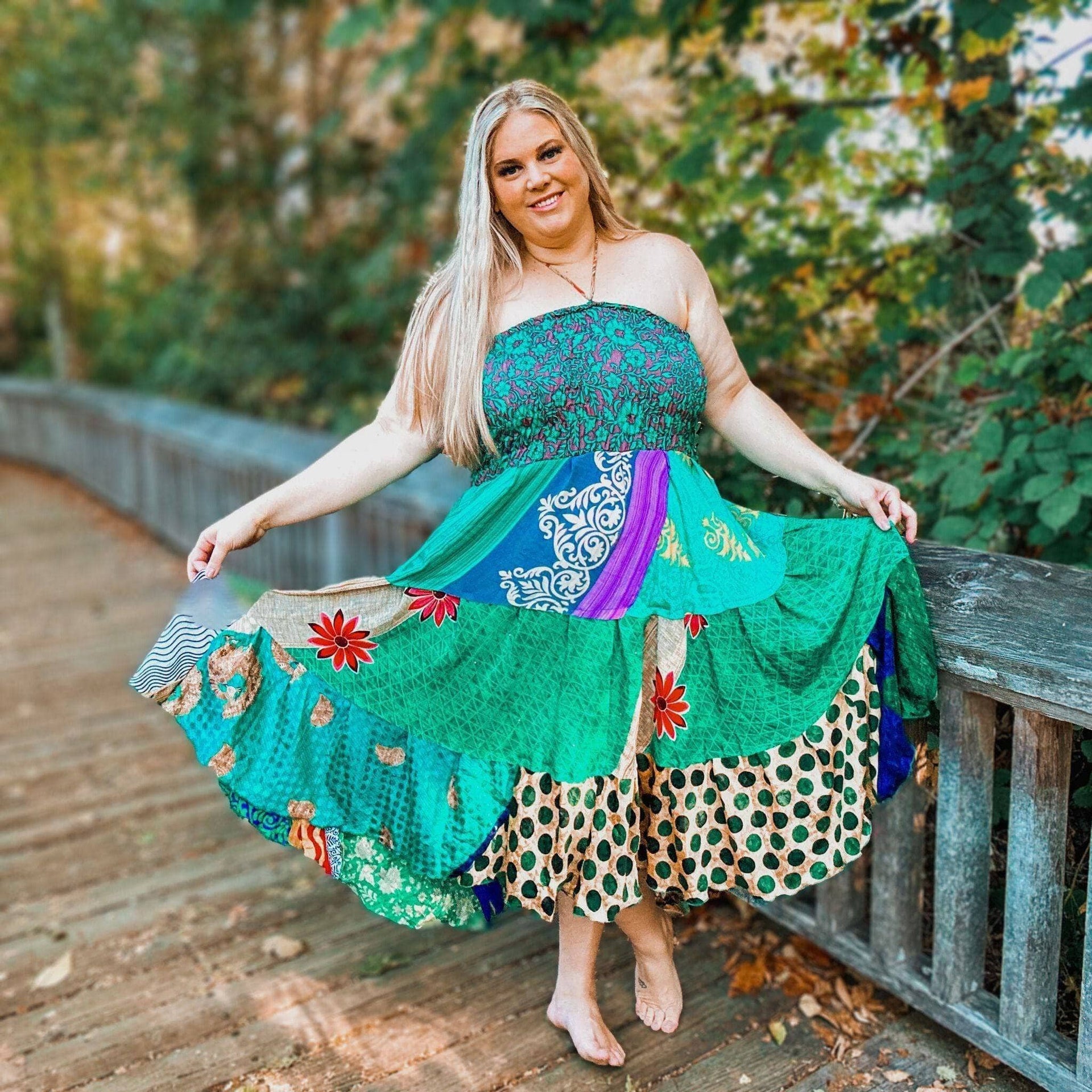 A woman wearing a vibrant, multi-colored bohemian patchwork midi dress with an A-line silhouette and sleeveless design.