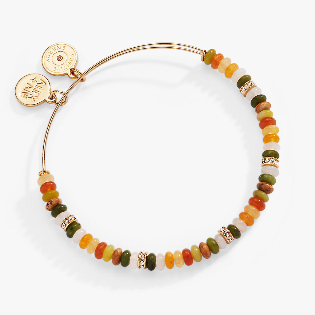 A gold-tone expandable bangle featuring multi-color faceted gemstone beads in earthy tones.