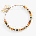 A gold-tone expandable bangle featuring multi-color faceted gemstone beads in earthy tones.