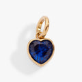 September birthstone heart charm in gold with a deep blue crystal, minimalist style
