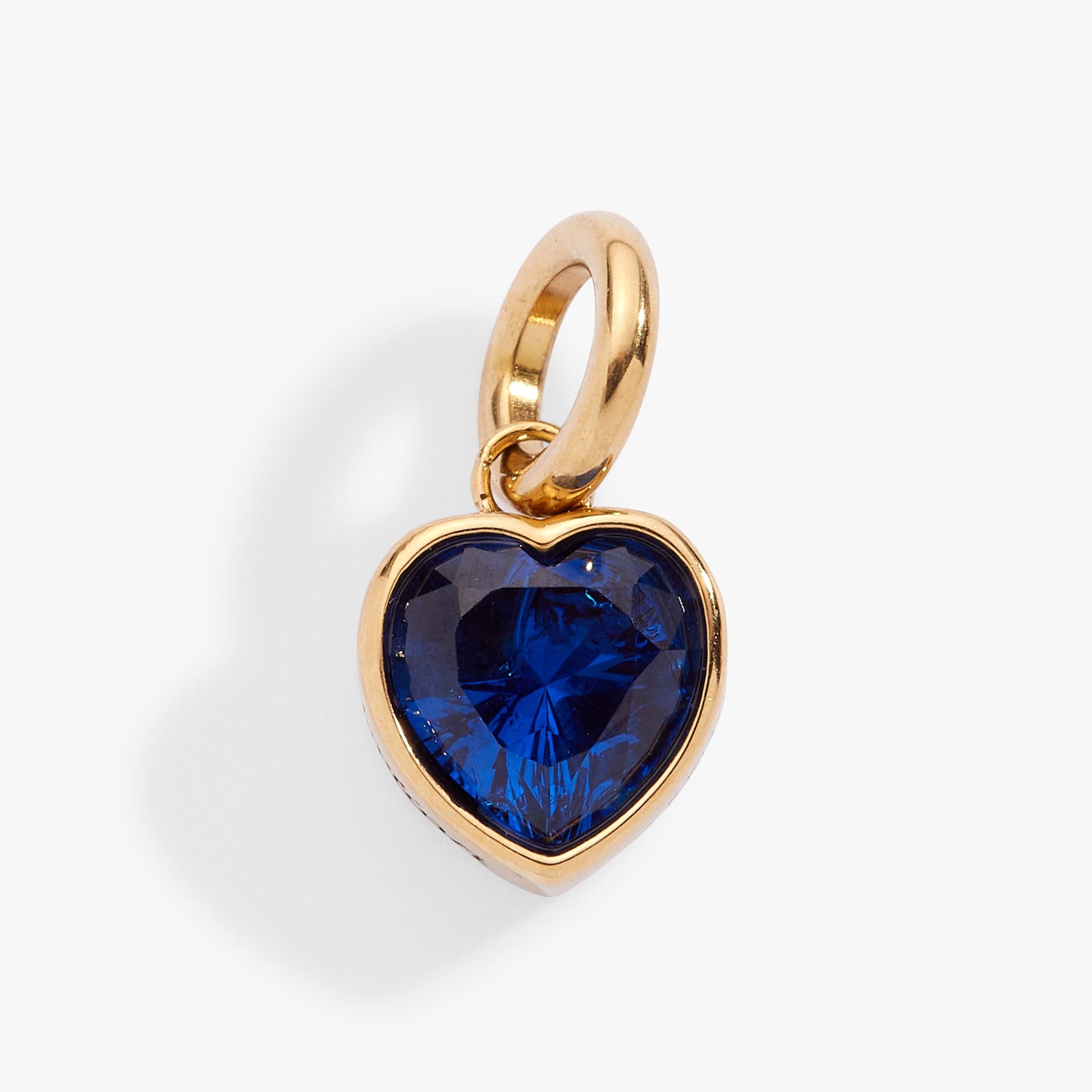September birthstone heart charm in gold with a deep blue crystal, minimalist style