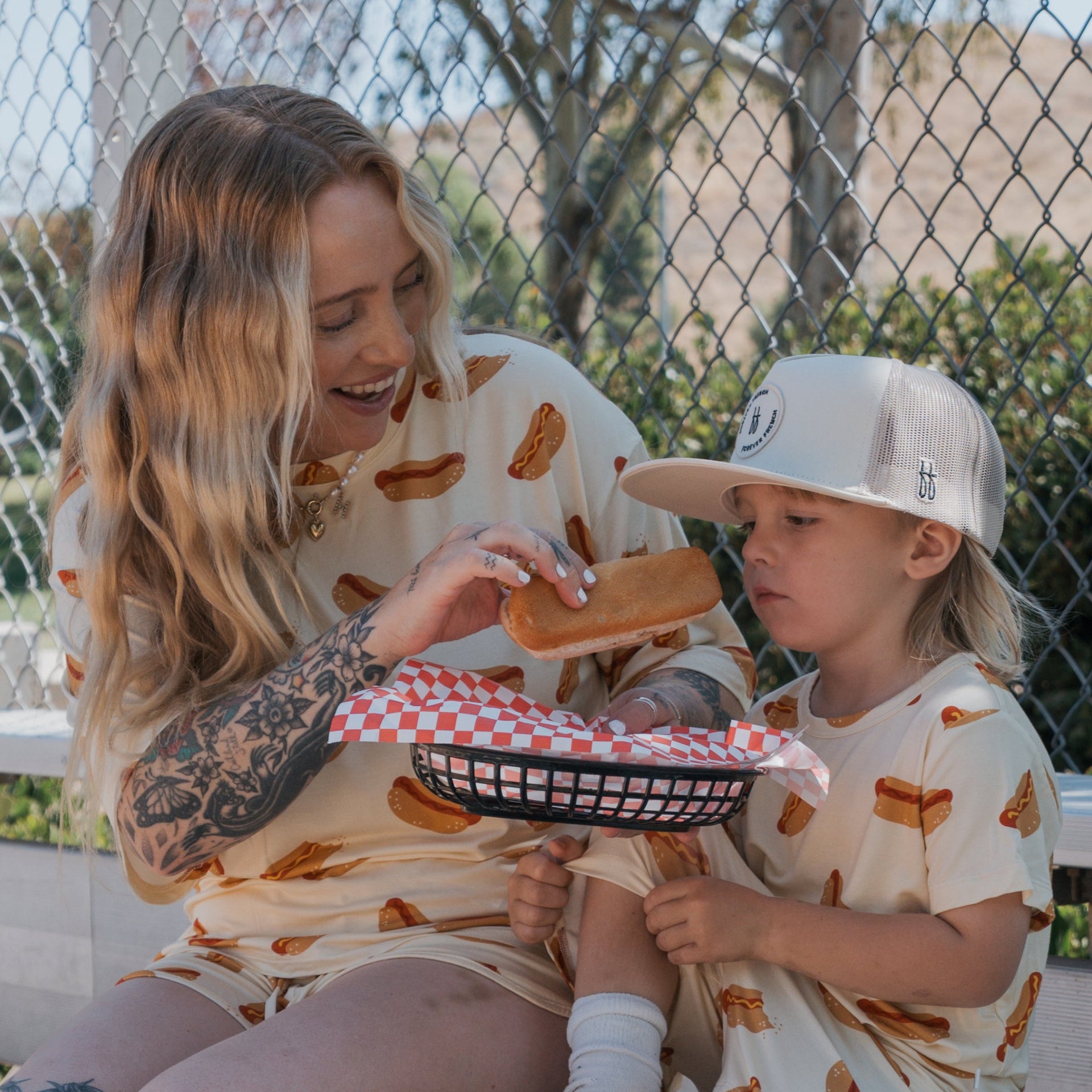 Women wearing a casual cream and brown hot dog print bamboo lounge set consisting of an oversized tee and drawstring shorts.