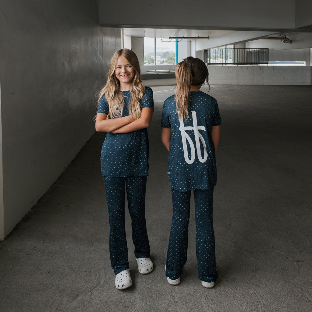 Child wearing a soft navy and white polka dot short sleeve bamboo lounge set with flare pants.