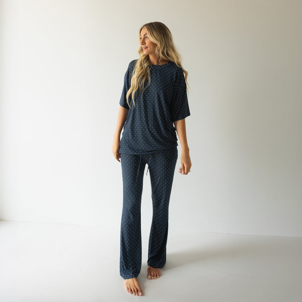 Woman wearing a navy and white polka dot oversized short sleeve bamboo lounge set with flare pants.