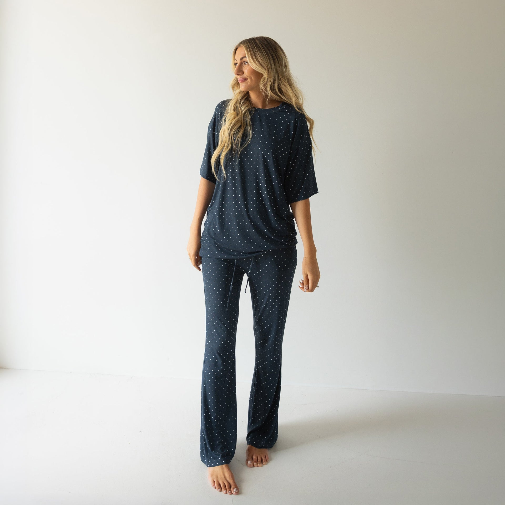 Woman wearing a navy and white polka dot oversized short sleeve bamboo lounge set with flare pants.