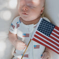 Baby wearing a white, red, and blue Americana ribbed bamboo shortie zip romper