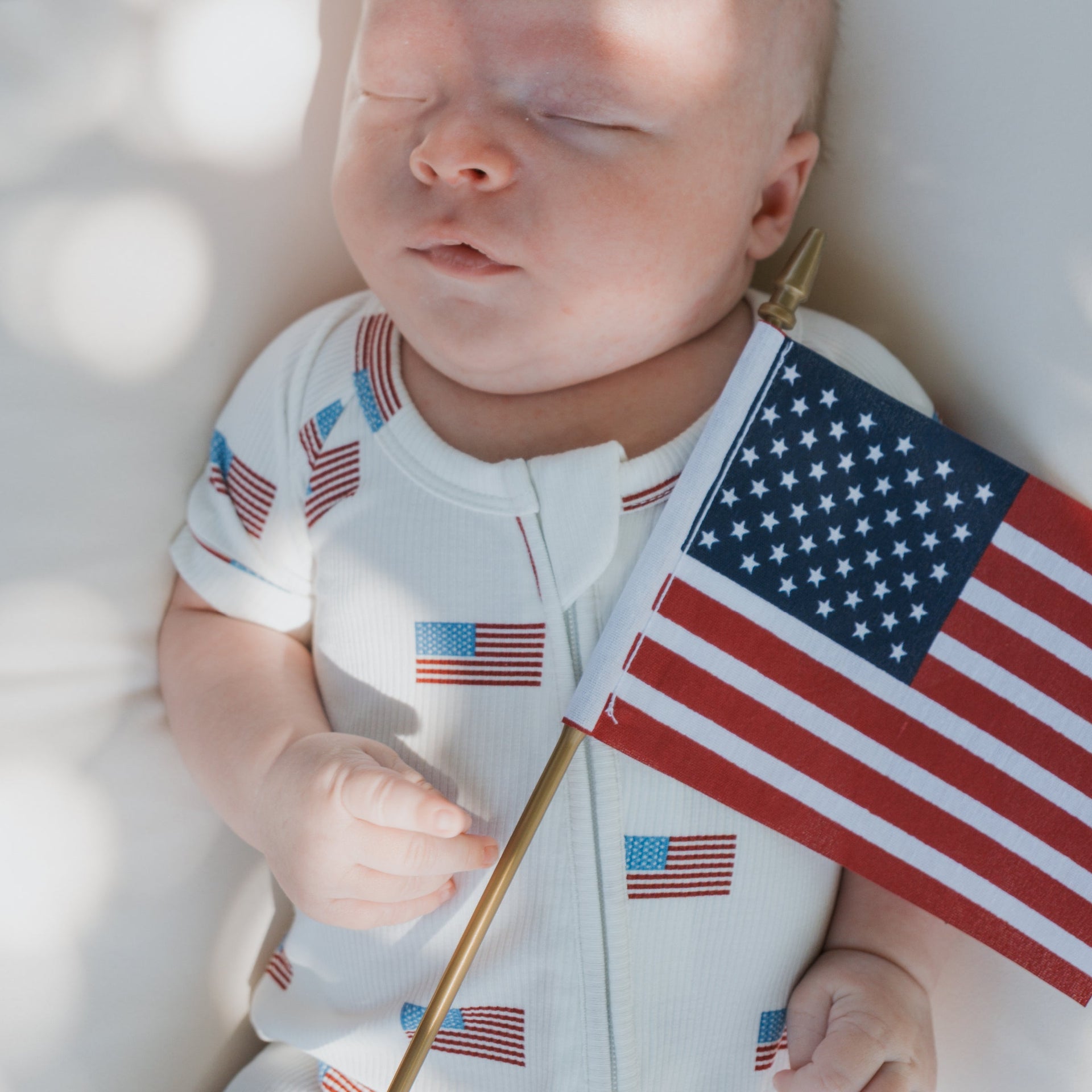 Baby wearing a white, red, and blue Americana ribbed bamboo shortie zip romper