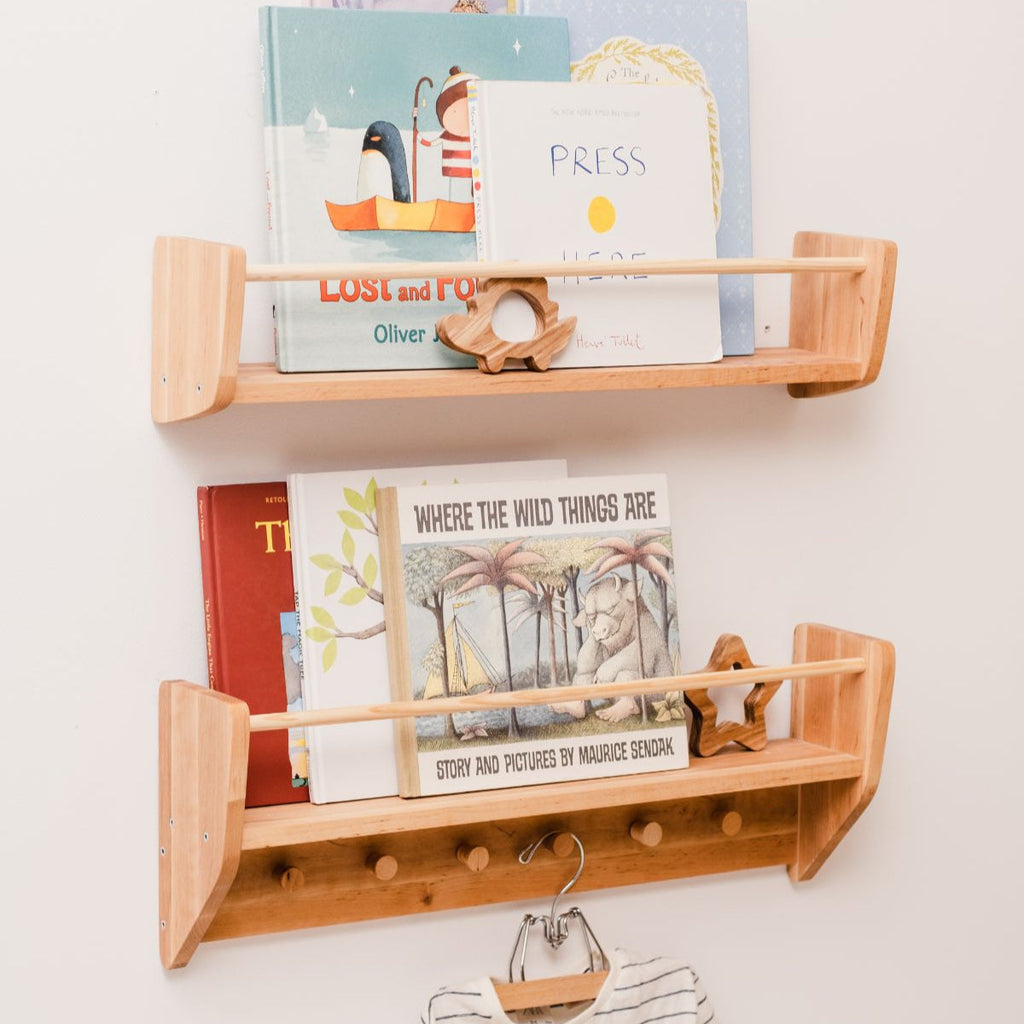 Wall-mounted wooden nursery shelf with hooks holding books and small items