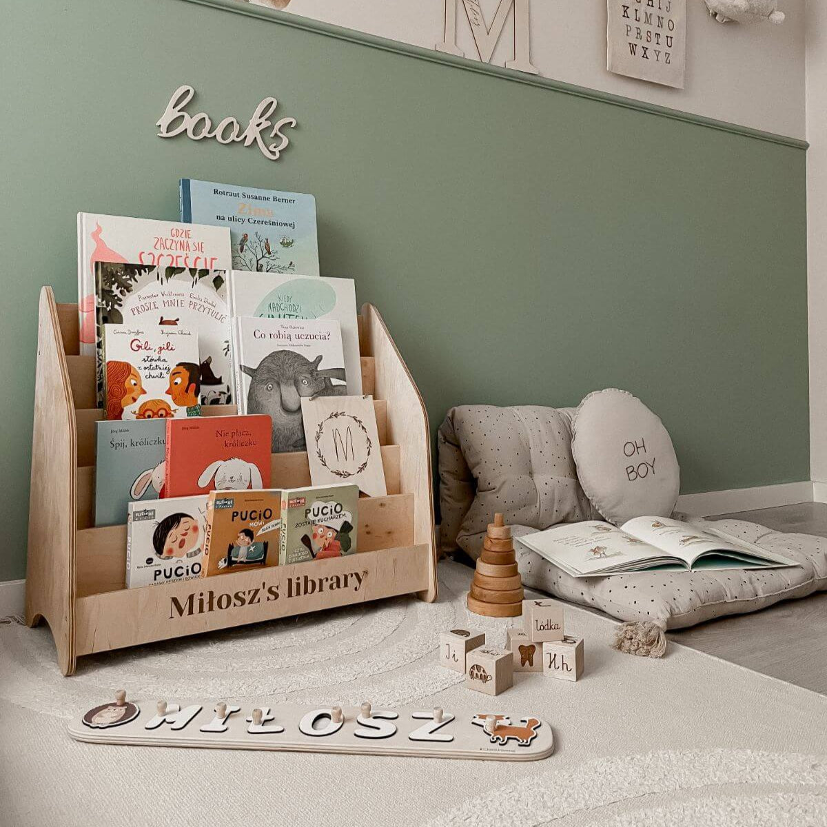 Wooden front-facing bookshelf filled with children's books in a bright, modern nursery.