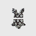 Girl wearing a dark brown and white two-piece swimsuit with a seashell print.