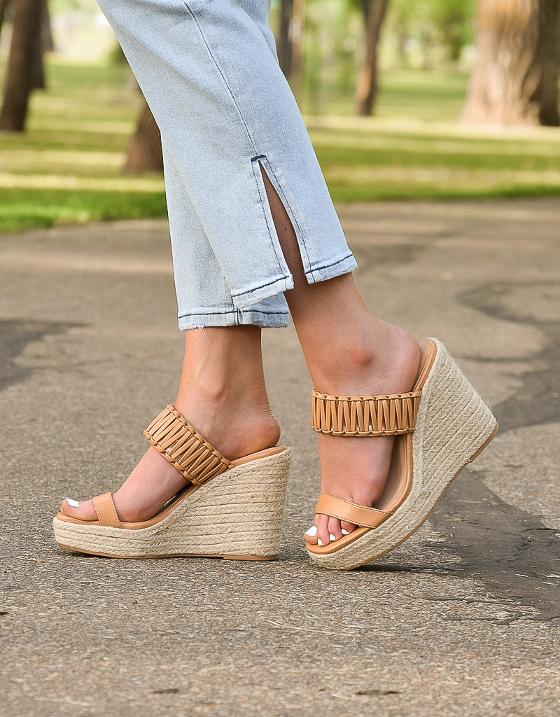 A pair of Atlas Wedge sandals in a natural tan color featuring a minimalist bohemian design.