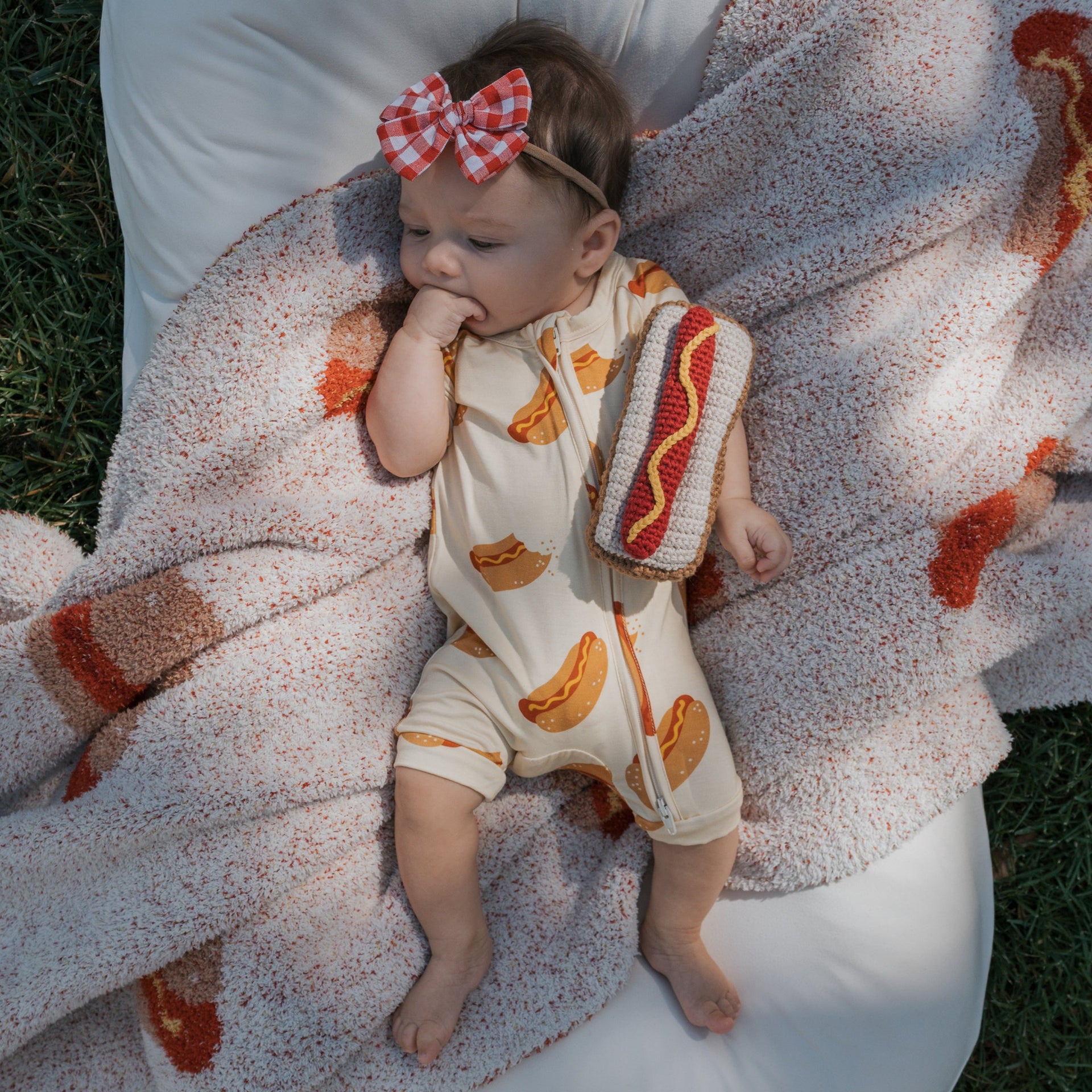 Newborn baby wearing a bamboo shortie zip romper with a hot dog pattern