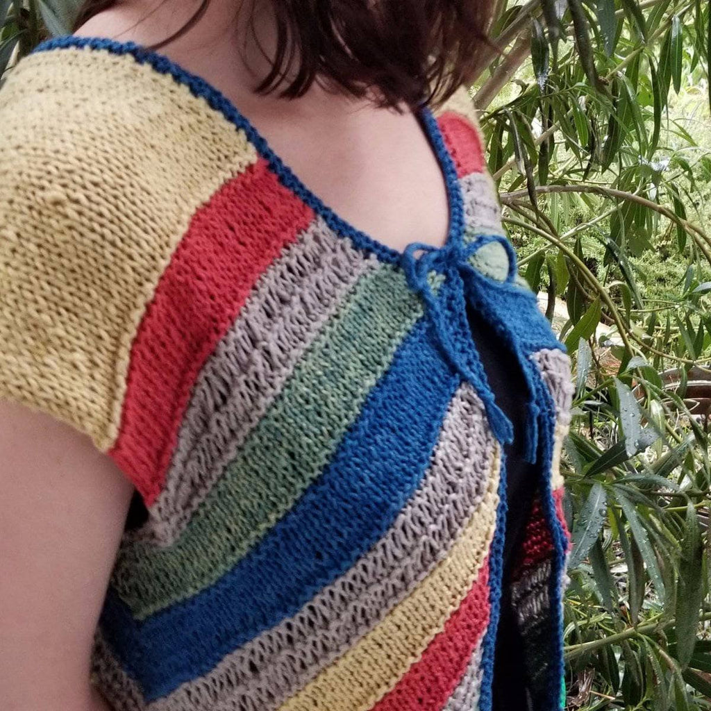Close up of Sierra Nevada Springtime Cardigan knitting kit featuring dusty-rose, pale-pink, navy-blue, and slate-blue yarn.
